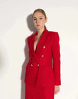 Zoom sur le blazer chic femme texturé rouge, détaillant les boutons dorés et le style élégant.