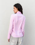 Détail de la chemise femme cintrée rose pastel sur une femme, montrant la coupe élégante et ajustée, vêtue d’un jean.