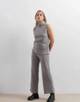 Femme montrant un gilet sans manche femme, habillée en ensemble col roulé et pantalon large gris pour un look moderne.