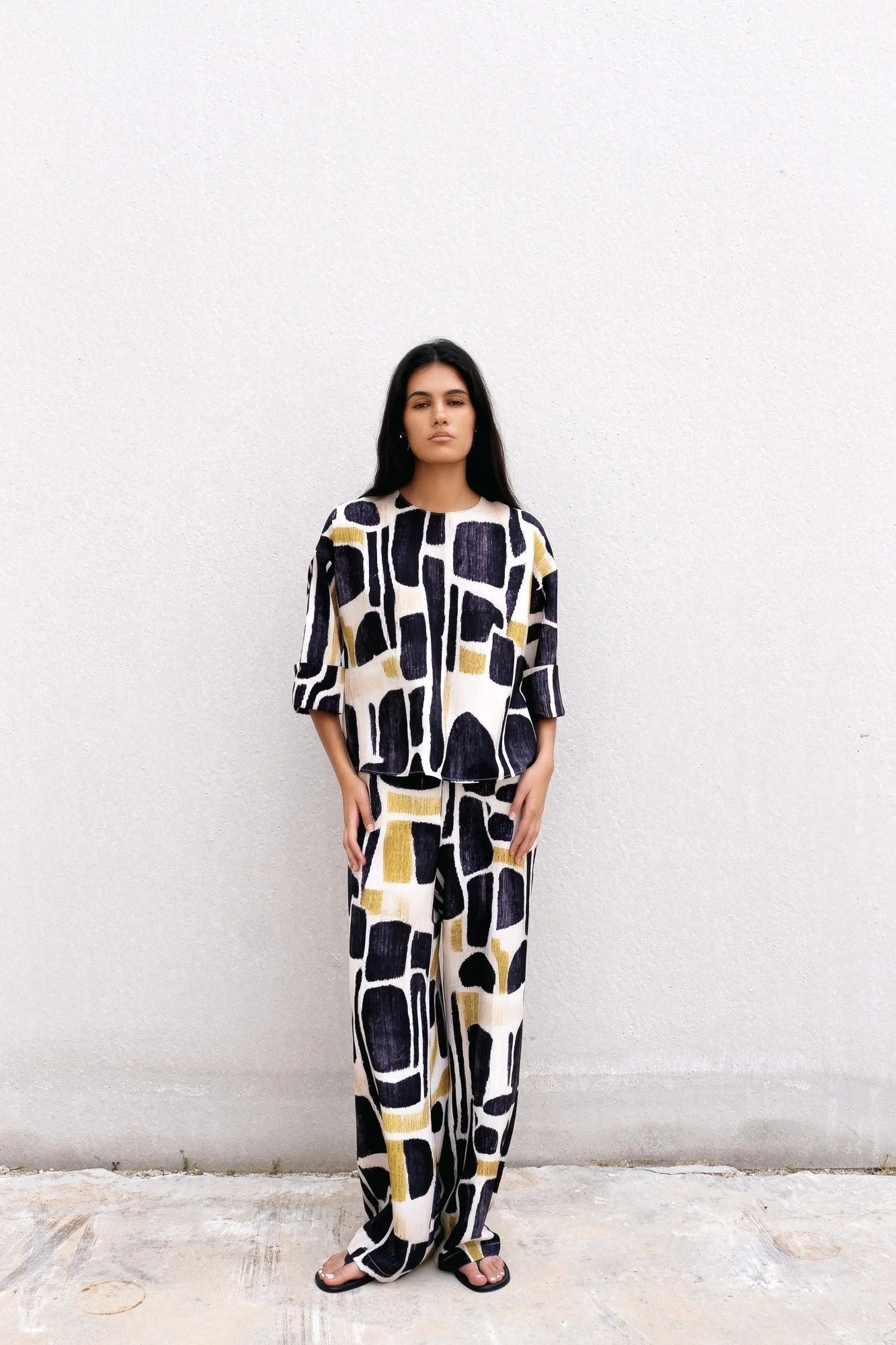 Femme portant un ensemble fluide imprimé abstrait noir et or, vêtement fluide femme