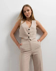 Femme affichant son gilet de costume femme court beige élégant et confortable, avec une pose décontractée mais élégante, pour un style moderne. Idéal pour toutes occasions.