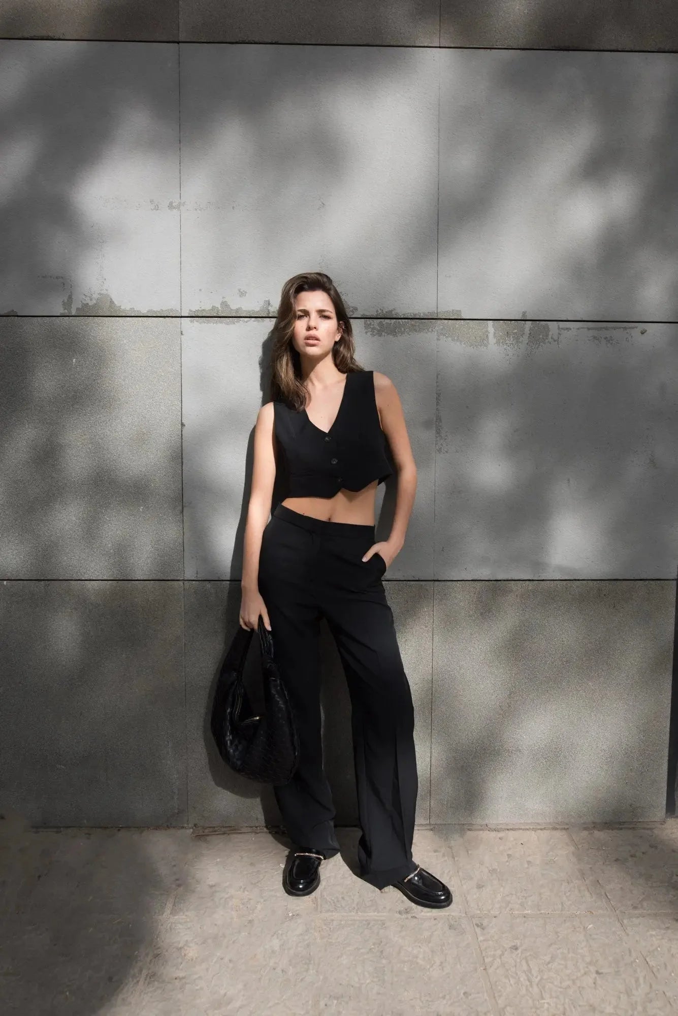 Femme en gilet court noir crop top et pantalons larges pour une touche tendance