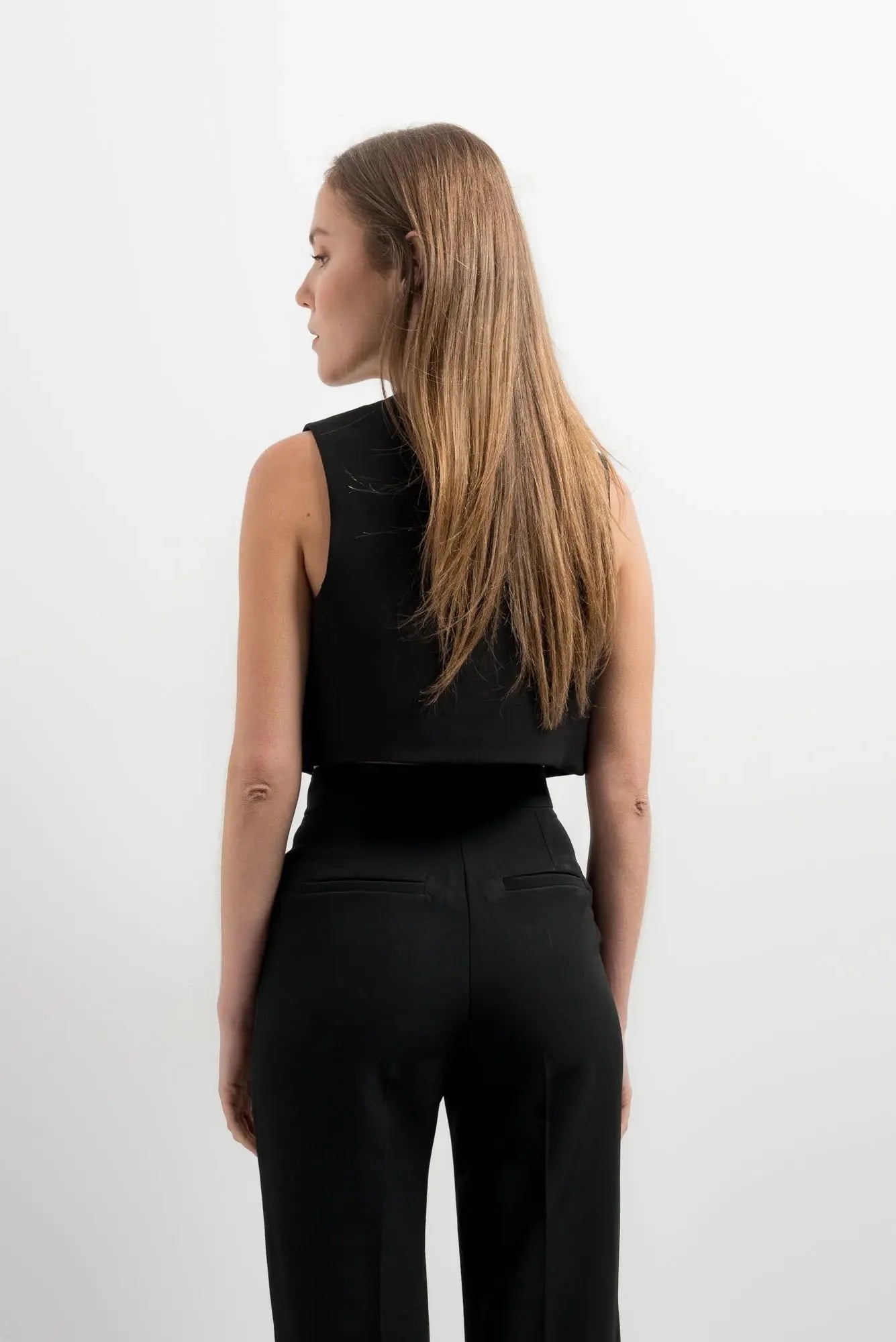 Femme portant un gilet court noir et un pantalon pour une touche tendance