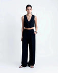 Modèle présentant un gilet costume femme court avec boutons, assorti à un pantalon noir pour un look chic.