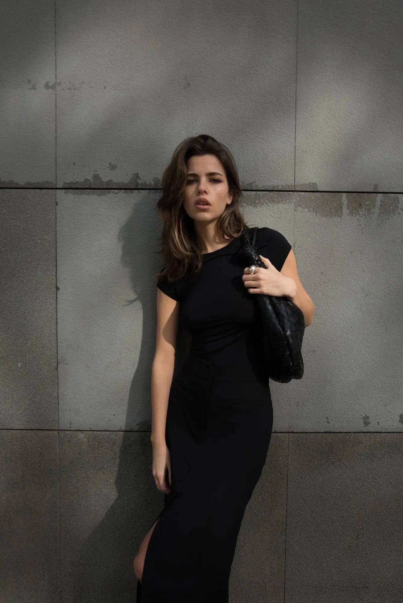 Détails d'une jeune femme avec une jupe noire fendue, accentuant le glamour et la modernité de la mode actuelle.