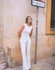 Femme en vest blanc chic et pantalon évasé dans l’ensemble blanc chic femme