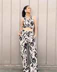 Mannequin affichant un style chic dans un pantalon fluide palazzo imprimé floral noir et blanc - taille élastiquée, légèreté et confort, les mains dans les poches. Pantalon à motif femme.