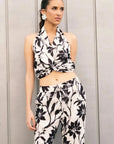 Modèle portant un pantalon fluide palazzo imprimé floral noir et blanc - taille élastiquée, légèreté et confort, avec un top noué, parfait pour un look d'été décontracté. Pantalon à motif femme.