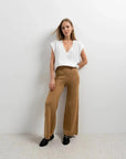 Modèle féminin en pantalon tricot à jambes larges couleur camel et t-shirt blanc, alliant style moderne et confort. Parfait pantalon tricot femme pour diverses occasions.