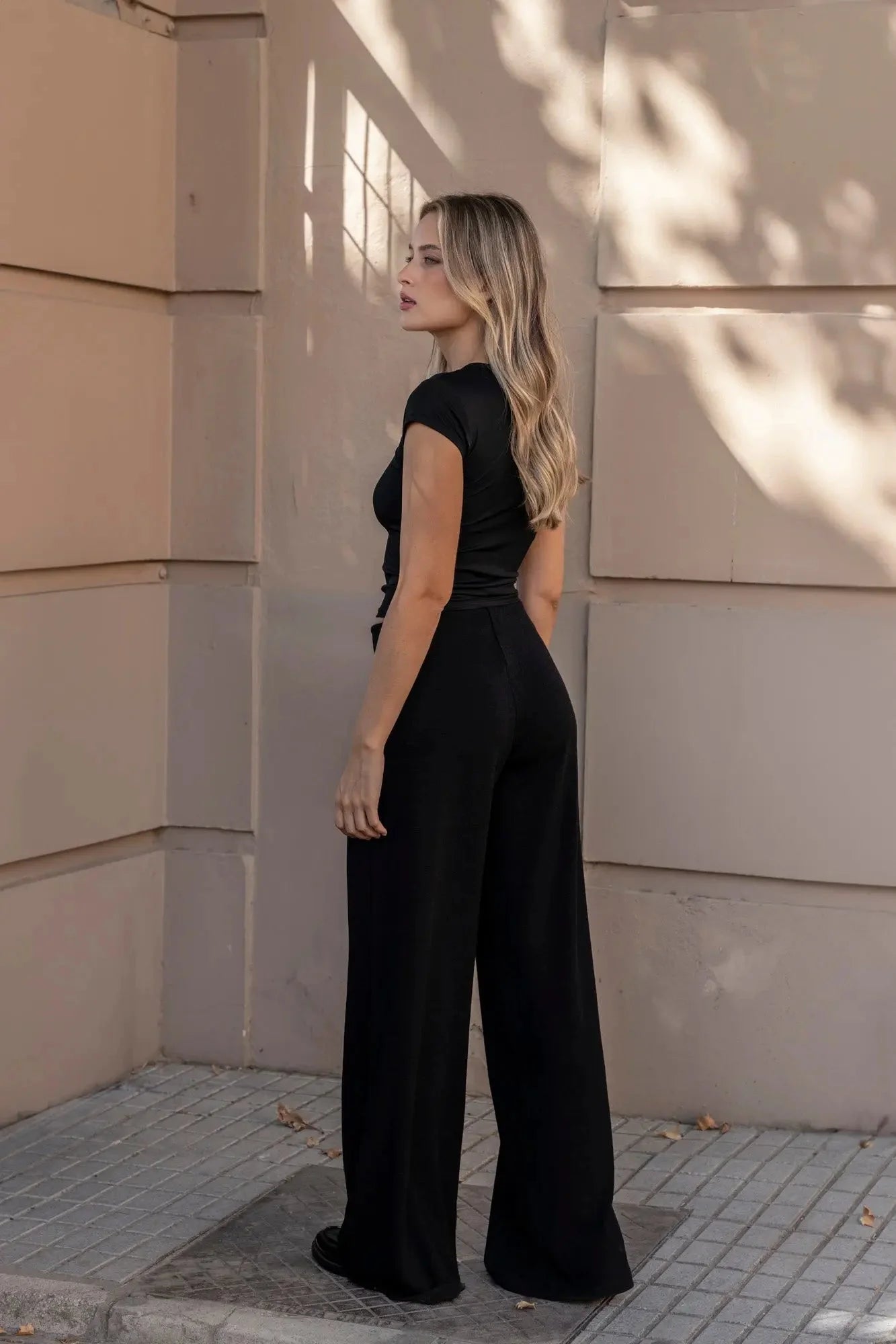 Femme portant un ensemble pull asymétrique et pantalon à jambes larges en tricot