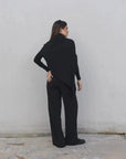 Femme vue de dos dans un ensemble pull asymétrique et pantalon à jambes larges, illustrant la silhouette élégante du pantalon large femme.