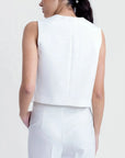 Détail du dos d'une femme dans un gilet sans manches chic blanc, style tailleur, sur un fond neutre.