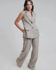 Modèle posant fièrement dans un gilet sans manches femme chic à rayures fines élégant et pantalon assorti, incarnant le style moderne. Gilet costume femme pour un style polyvalent.