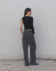 Vue arrière du haut asymétrique femme noir à une épaule, assorti à un pantalon gris pour un ensemble chic et moderne.