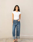 Une jeune femme porte un jean à jambe large et ourlets retroussés, mettant en avant le style casual du jean ample femme avec un tee-shirt blanc.
