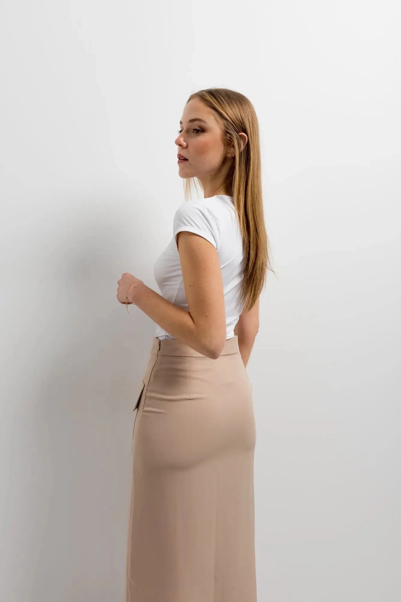 Femme élégante avec jupe cargo femme beige, posée d'une manière décontractée, mettant en avant ses accessoires.
