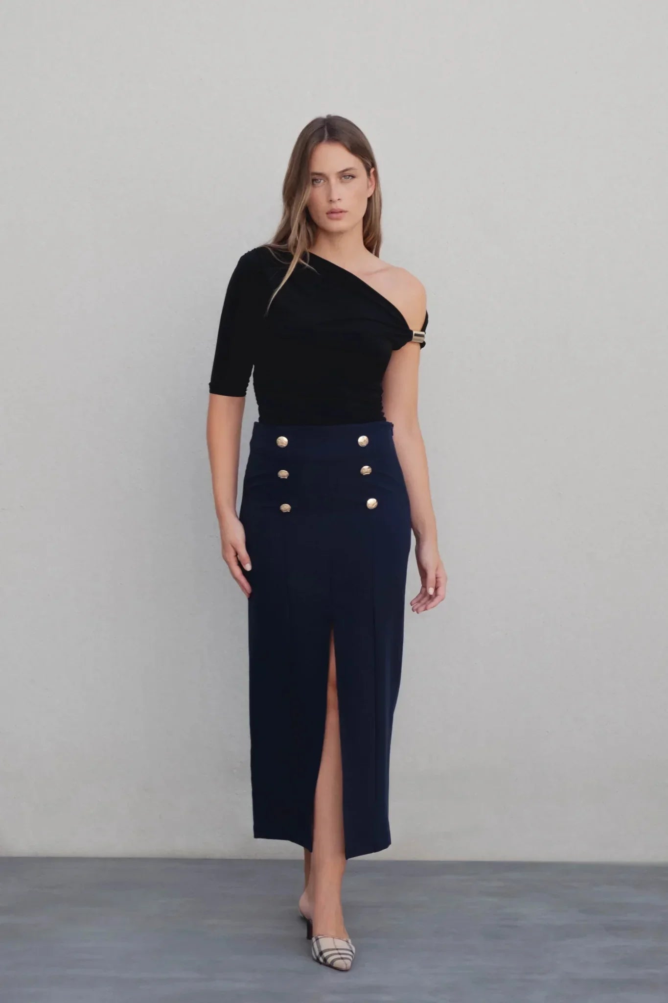 Vêtements femme à boutons dorés : top noir asymétrique et jupe marine à fente