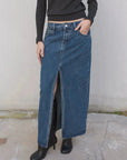 Détail sur une jupe jean longue avec fente haute, mettant en avant le design tendance et la praticité pour un look stylish en toutes situations.