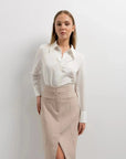Femme portant une jupe midi fente beige avec chemise blanche, style élégant et chic