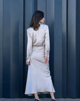 Vue arrière d'un modèle avec une jupe satin longue et chemise assortie, démontrant le style sophistiqué de la jupe midi en satin et ensembles assortis.
