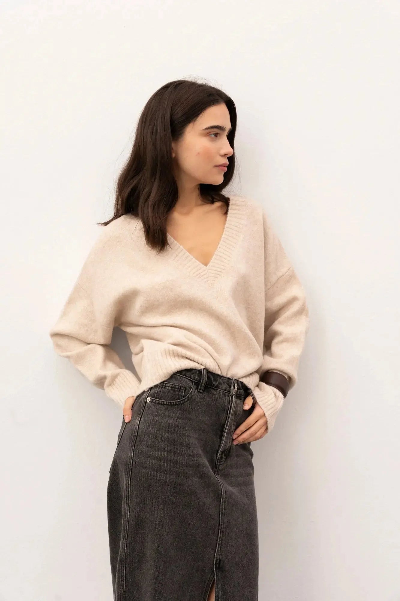 Jupe midi polyvalente en denim gris avec fente, porté par une femme en pull beige