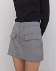 Zoom sur une jupe short mini à motifs portée avec un haut noir, montrant le design pratique des poches.