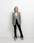 Femme habillée chic avec un blazer sur des leggings évasé noir à fentes, parfaite pour une sortie professionnelle.