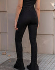 Vue arrière d'une femme en leggings évasé noir à fentes, mettant en avant la coupe flatteuse.