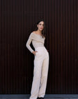 Modèle en pantalon droit femme beige, stylisé avec un haut à épaules dénudées, illustrant le confort et l'élégance intemporelle.