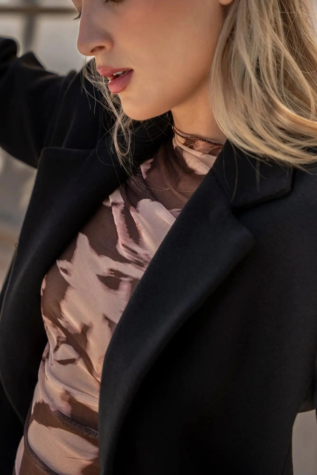 Femme portant un manteau ajusté en laine pour femme avec blazer noir et haut transparent