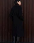 Femme de dos dans un manteau long chaud femme noir à double boutonnage, affichant une silhouette élégante.