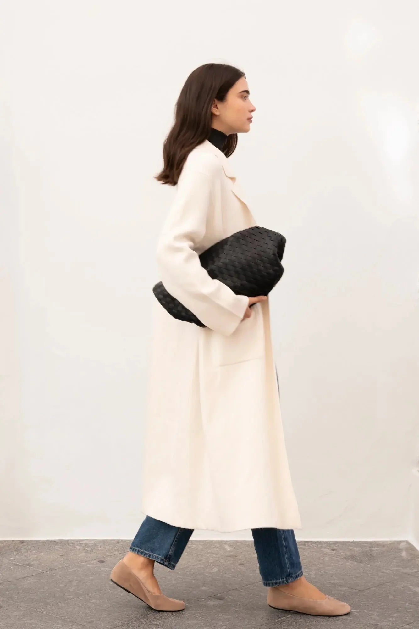 Détail de femme avec un manteau en drap de laine en cardigan maille oversize cosy chic, en train de marcher, mix style décontracté.