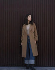 Femme portant un manteau long en laine double boutonnage camel, parfait pour l'hiver, mettant en valeur le manteau femme hiver long.