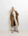 Femme élégante posant avec un manteau long en laine camel, un incontournable de la saison hivernale, le manteau femme hiver long.