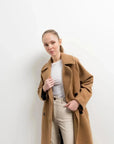 Femme en manteau long en laine double boutonnage camel avec un look stylé, idéal pour les jours froids, le manteau femme hiver long.