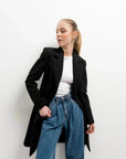 Manteau Long Chaud Femme: Détail sur une femme présentant un manteau noir élégant, montrant comment le confort et la mode se rencontrent.