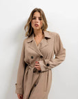 Modèle portant un manteau trench oversize long marron clair, mettant en avant le style moderne et chic du trench coat femme.