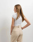 Vue arrière d'une femme en t-shirt blanc et pantalon court plissé taille basse beige, montrant le style moderne du pantalon court noir femme.