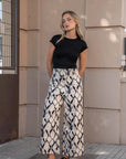 Pantalon motif femme palazzo imprimée, image d'un modèle portant un t-shirt noir et le pantalon motif femme, style élégant et confortable avec poches.
