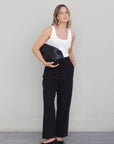 Femme posant avec un pantalon à pince femme noir et un sac élégant, combinant confort et style moderne.