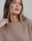 Femme avec pull laine femme col rond marron, montrant une allure chic et décontractée.