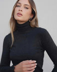 Modèle portant un pull col roulé femme gris foncé ajusté élégant, parfait pour un look chic.