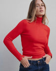 Pull col roulé femme rouge intemporel ajusté en maille fine, modèle féminin portant le pull avec une coupe élégante.