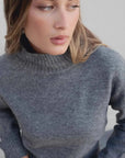 Modèle féminin portant le pull col roulé femme court gris, mettant en avant le col montant.