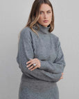 Femme posant avec le pull col roulé femme gris, style moderne et chic.
