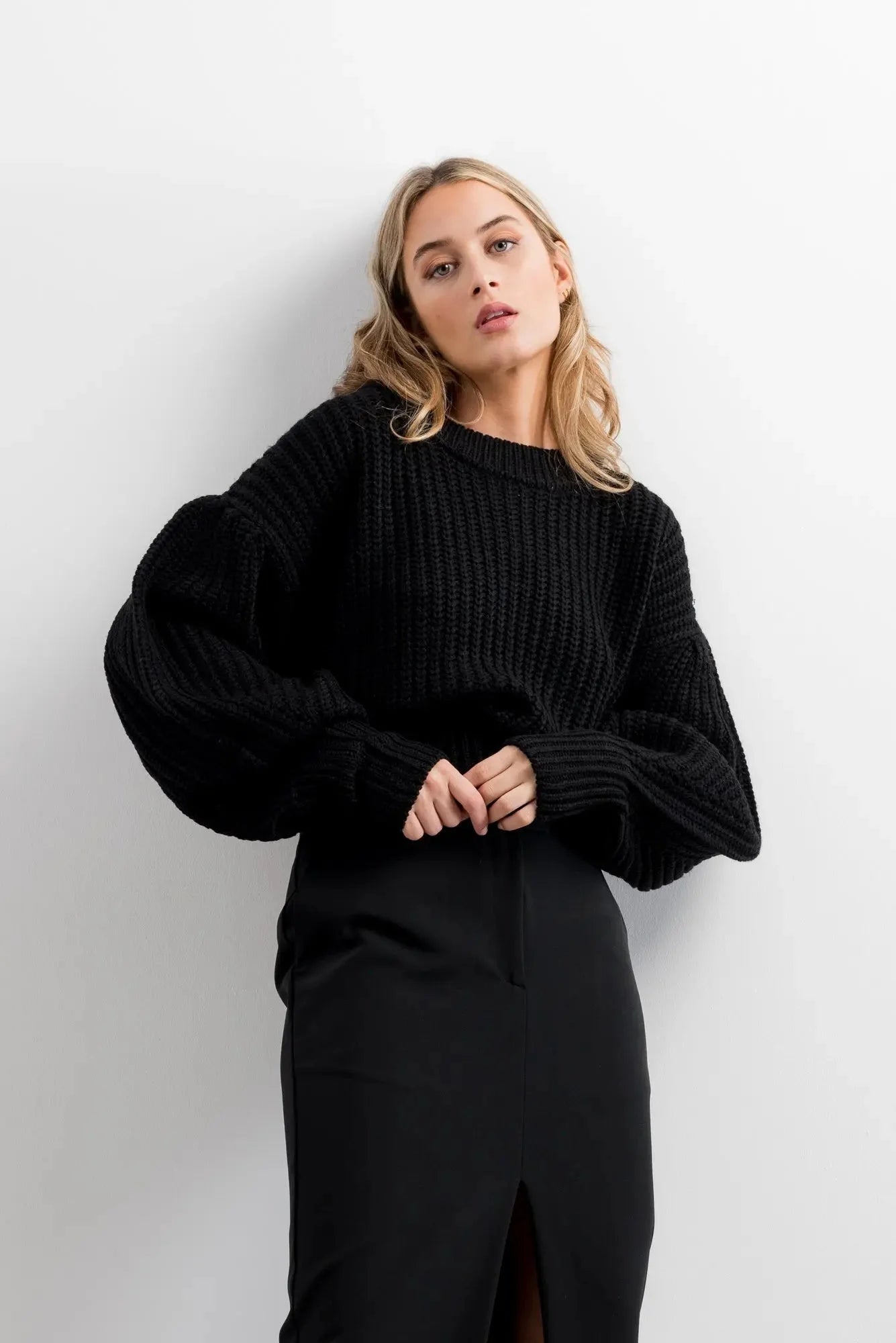 Femme portant un pull crème en tricot surdimensionné manches ballon et jupe midi noire