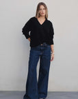 Modèle stylé avec un pull oversize noir col V associé à un jean large, parfait pour une tenue casual chic avec pull laine femme.