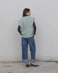 Femme avec un pull sans manche femme oversize en tricot col V doux, vêtue d'un jean, capturant un style à la fois chic et décontracté.