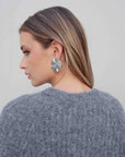 Vue arrière du modèle en pull maille oversize gris, soulignant le design élégant et les boucles d'oreilles stylées.