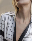 Gros plan sur le col et le décolleté d'une robe chemise longue chic à rayures noires et blanches, mettant en avant son design élégant.